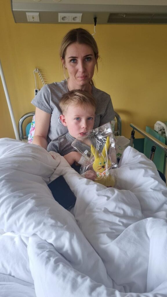 Mama z kilkuletnim chłopcem w szpitalnym łóżku. Dziecko trzyma szmacianego zająca.