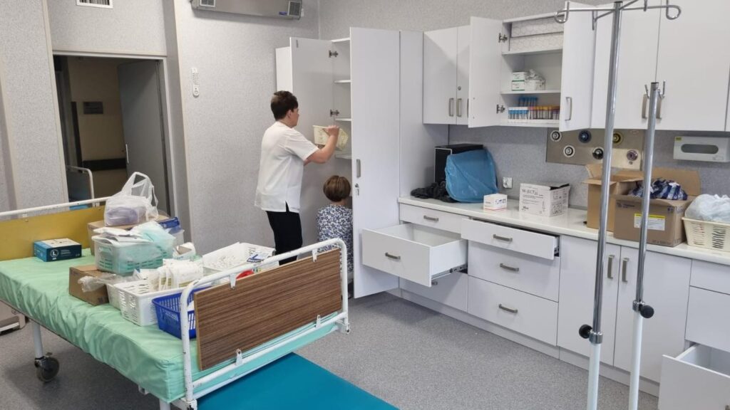 Oddział Gastroenterologiczny. Dwie pielęgniarki układają wyposażenie i materiały medyczne na półkach. 