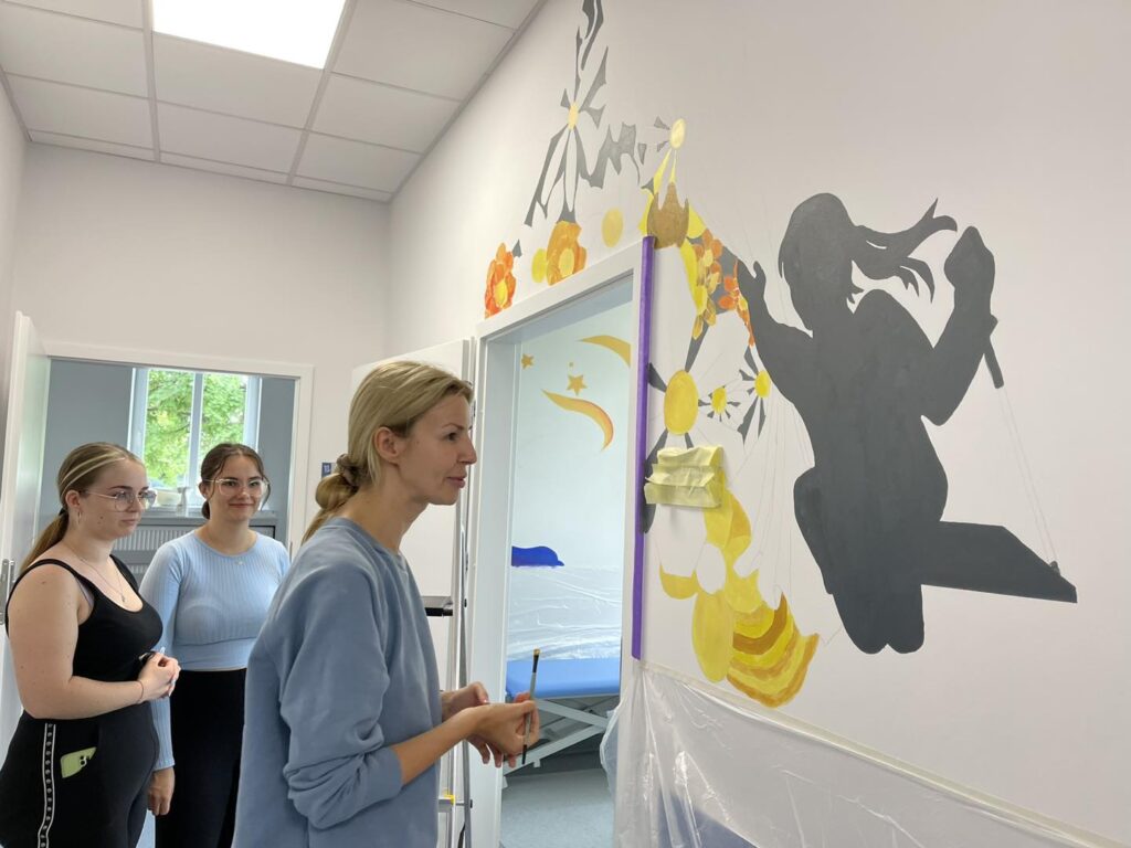 Studentki malują ściany na oddziale rehabilitacji dziecięcej.